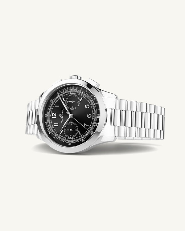 En rund herrklocka i rodiumpläterat silver från WALDOR & CO. med svart sunray urtavla och en sekundvisare. Seiko urverk. Modellen är Chrono 39 Porto Cervo.