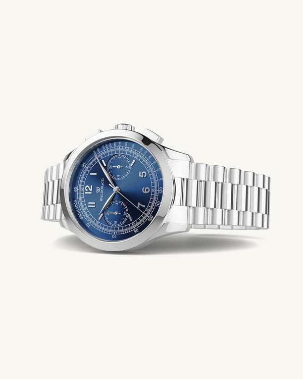 En rund herrklocka i rodiumpläterat silver från WALDOR & CO. med blå sunray urtavla och en sekundvisare. Seiko urverk. Modellen är Chrono 39 Porto Cervo.