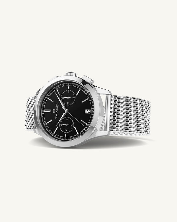 En rund herrklocka i rodiumpläterat silver från WALDOR & CO. med svart sunray urtavla och en sekundvisare. Seiko urverk. Modellen är Chrono 39 Sardinia 39mm.
