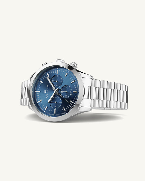 En rund herrklocka i rodiumpläterat silver från WALDOR & CO. med blå sunray urtavla och en sekundvisare. Seiko urverk. Modellen är Chrono 44 Como 44mm.