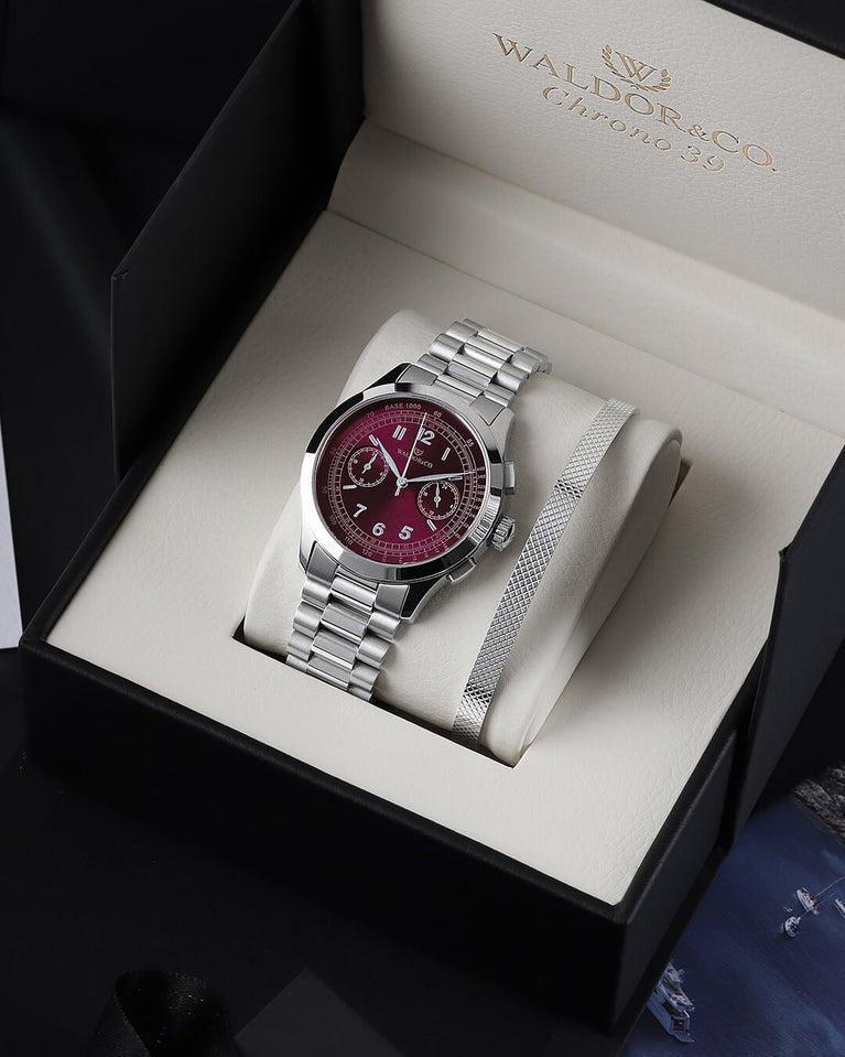 A round mens watch in rhodium-plated silver from Waldor & Co. with a burgundy colored sunray dial and a second hand. Seiko movement. The model is Chrono 39 Porto Cervo.