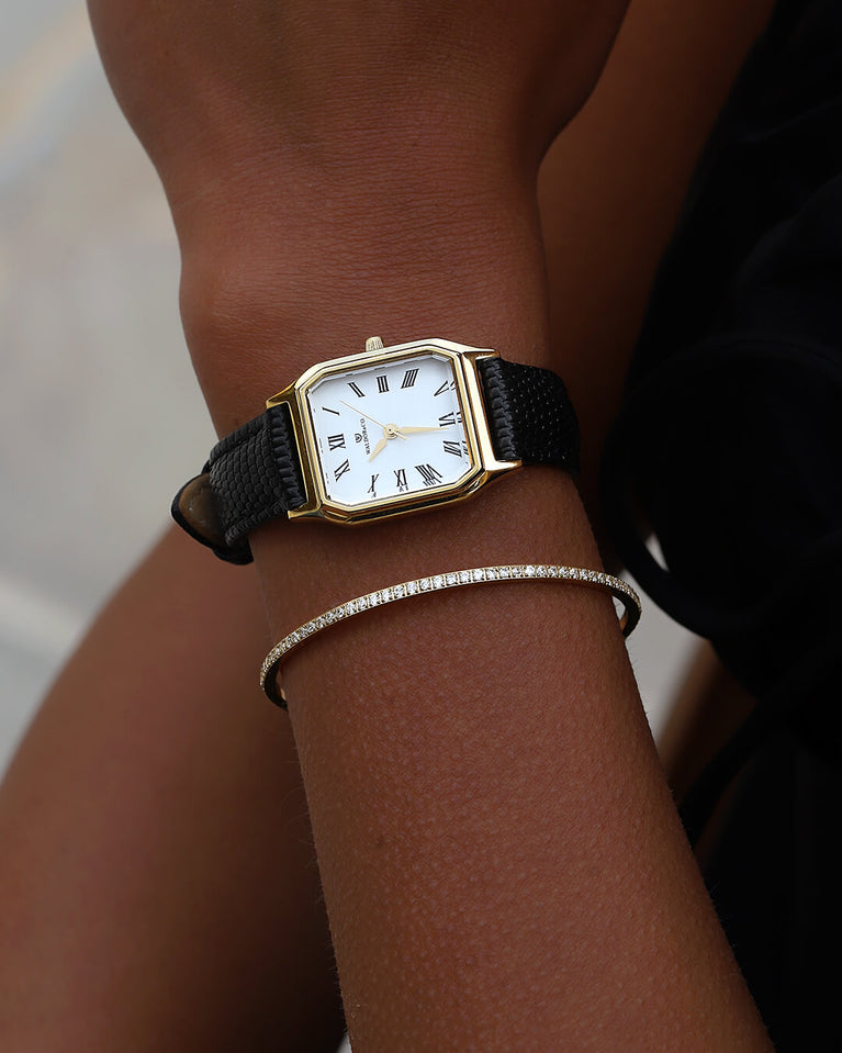 A square womens watch in 22k gold from Waldor & Co. with white Diamond Cut Sapphire Crystal glass dial. Strap in black Genuine leather. Seiko movement. The model is Eternal 22 Varenna. 