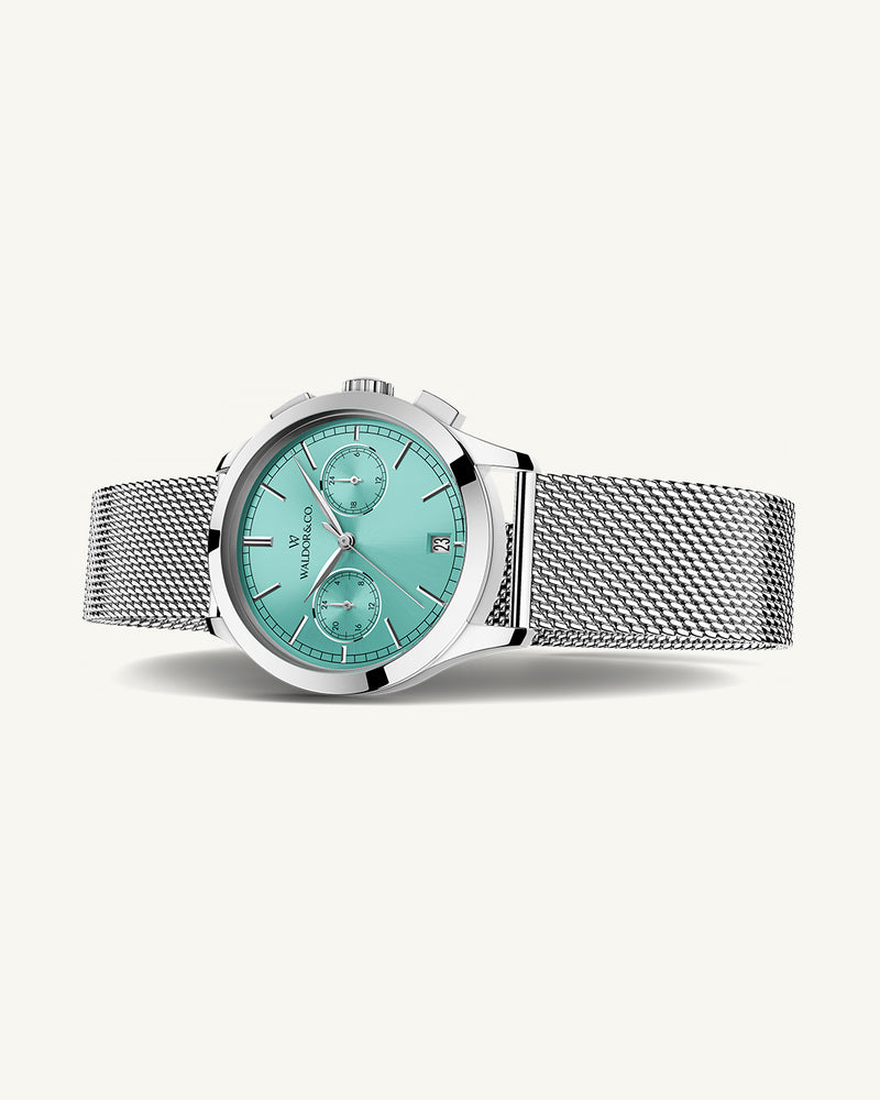 A round womens watch in rhodium-plated silver from Waldor & Co. with turquoise sunray dial and a second hand. Seiko movement. The model is Chrono 36 Sardinia 36mm.