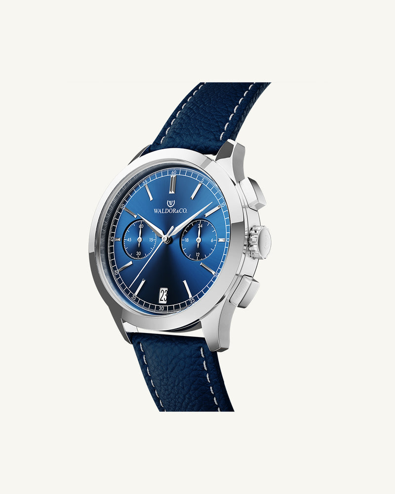 A round mens watch in rhodium-plated silver from Waldor & Co. with blue sunray dial and genuine blue leather strap. A second hand. Seiko movement. The model is Chrono 44 Sardinia 44mm.