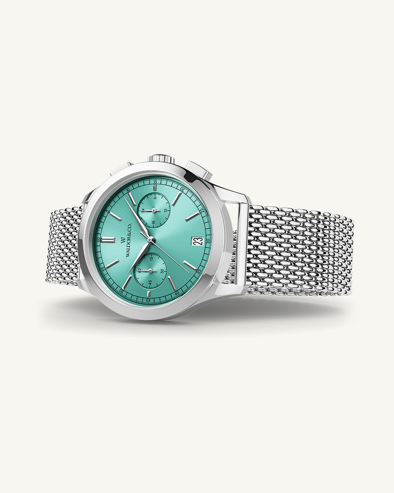 A round mens watch in rhodium-plated silver from Waldor & Co. with turquoise sunray dial and a second hand. Seiko movement. The model is Chrono 44 Sardinia 44mm.