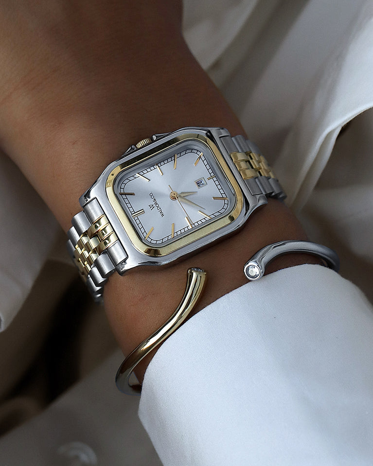  A square womens watch in silver and 14k gold from Waldor & Co. with silver sunray dial and a second hand. Seiko movement. The model is Delight 32 Chelsea 28x32mm.