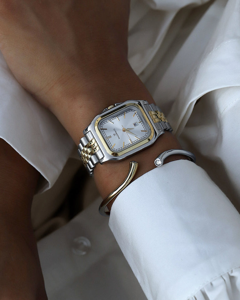  A square womens watch in silver and 14k gold from Waldor & Co. with silver sunray dial and a second hand. Seiko movement. The model is Delight 32 Chelsea 28x32mm.