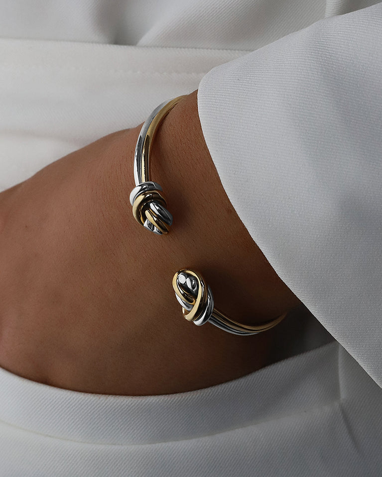 A Bangle in 14k-gold plated and silver polished 316L stainless steel from Waldor & Co. One size. The model is Dual Knot Twin Bangle Polished.