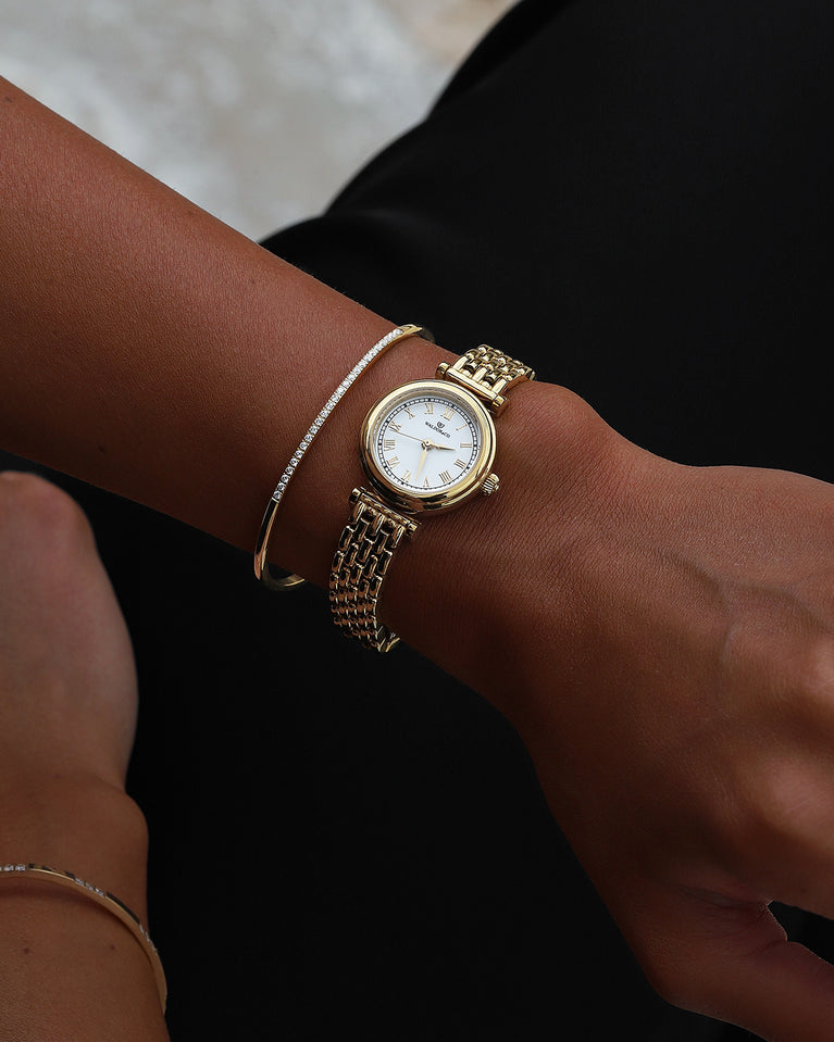 A round womens watch in 22k gold plated 316L stainless steel from Waldor & Co. with white Sapphire Crystal glass dial. Seiko movement. The model is Venia 24 Villefranche.