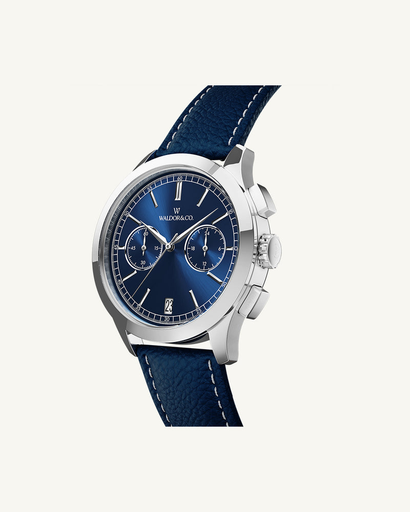A round mens watch in rhodium-plated silver from Waldor & Co. with blue sunray dial and genuine blue leather strap. A second hand. Seiko movement. The model is Chrono 44 Sardinia 44mm.