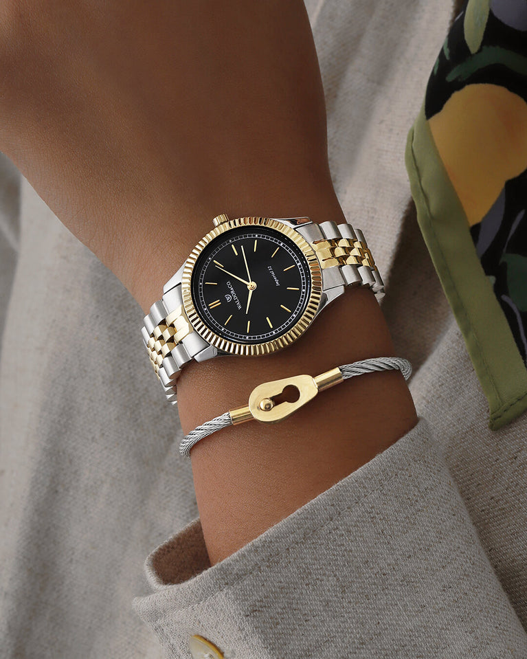  A round womens watch in silver and 22k gold from Waldor & Co. with black sunray dial and a second hand. Seiko movement. The model is Imperial 32 Positano 32mm.